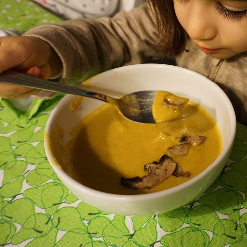 criança comendo sopa de abóbora e cogumelos