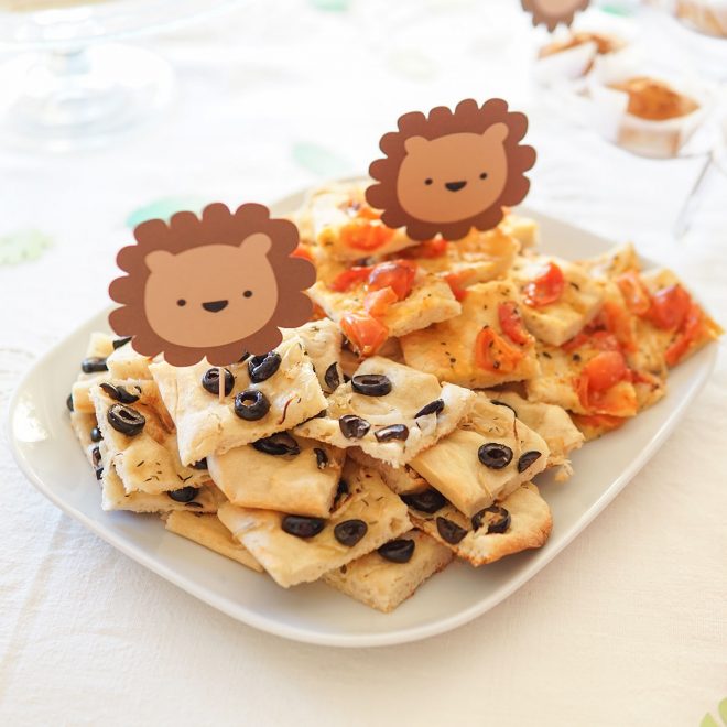 Prato com pedaços de focaccia de tomate e focaccia de azeitonas para a ementa da festa de aniversário do leão