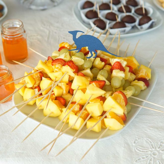 espetadas de fruta, com abacaxi, laranja, morango, manga e uva, para a ementa da festa de aniversário de dinossauros
