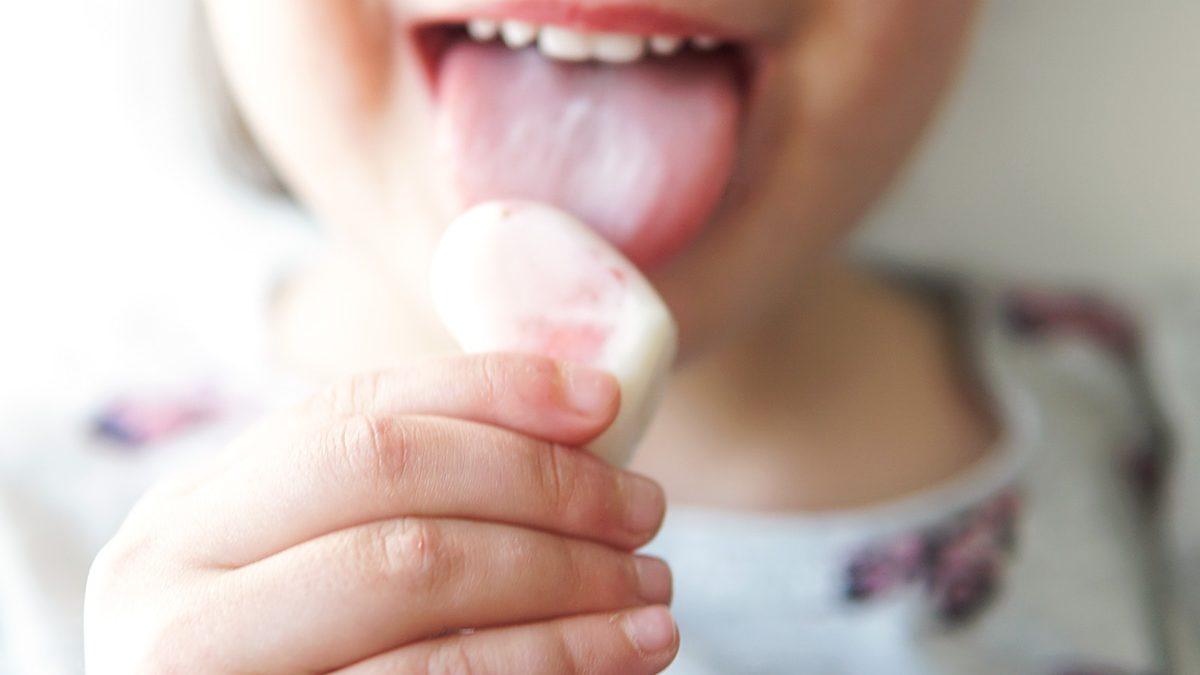 criança a comer um snack gelado de iogurte e morangos