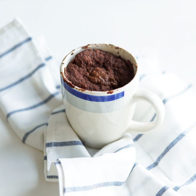 bolo na caneca de chocolate, em caneca com decoração azul e pano azul.