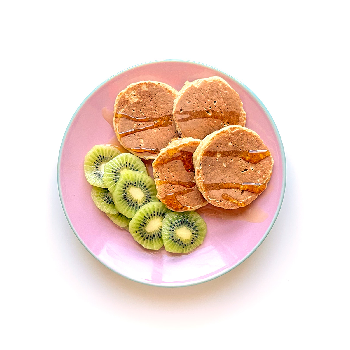 panquecas de aveia e maçã servidas com mel e kiwi num prato cor-de-rosa