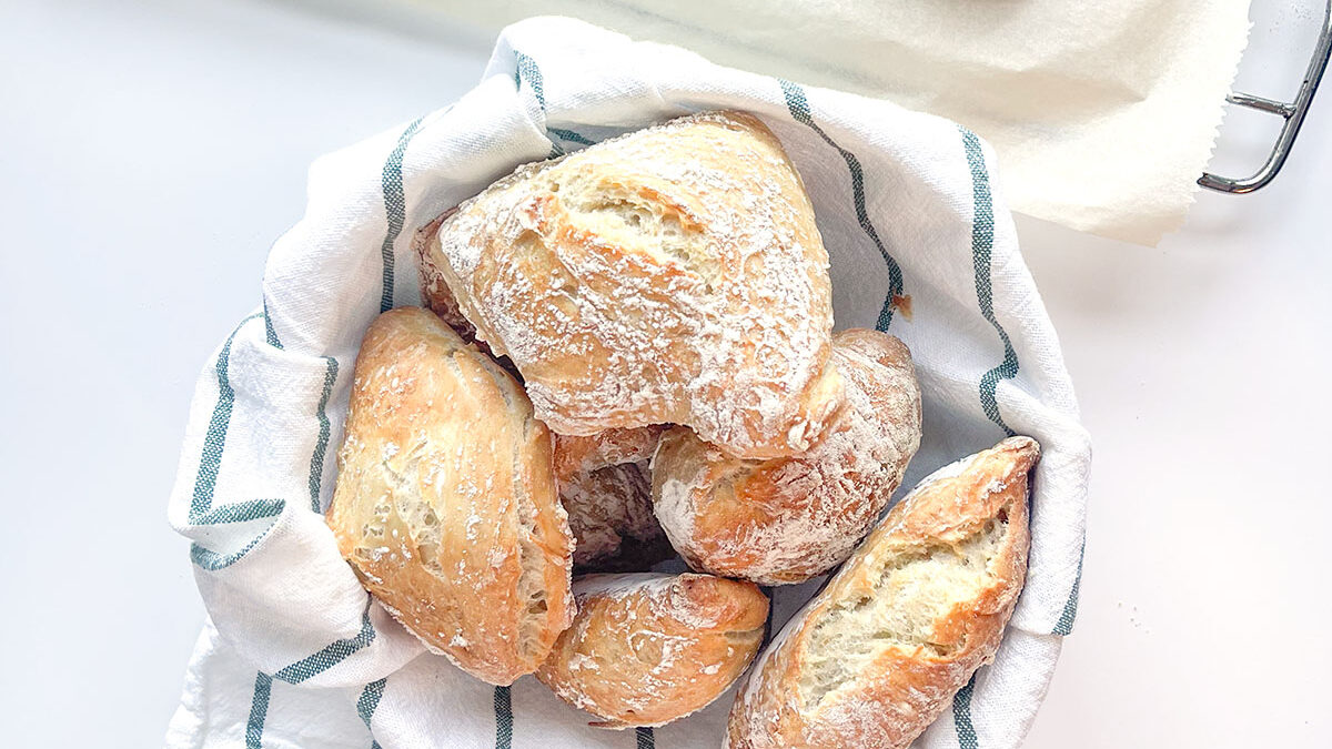 pão caseiro em cesto com pano de cozinha branco e verde
